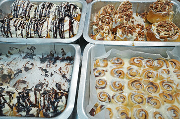 Close up assorted chocolate and nutty cinnamon rolls in aluminum trays