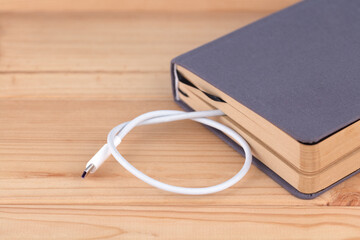The charging cable sticks out of the book