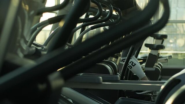 Athlete woman is walking on orbitrek in gym. Girl is working out on stepper for cardio intensity and endurance improvement