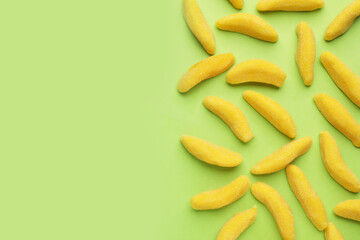 Tasty jelly candies in shape of banana on green background, flat lay. Space for text