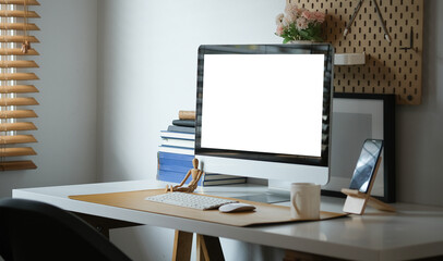 Computer with blank white display and supplies on white table.