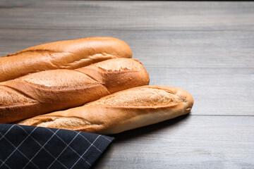 Tasty baguettes on wooden table, closeup. Space for text