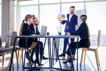 Successful meeting of business people, discussing new business ideas, using diagrams, sitting together. Modern office background. Meeting of business partners at the conference on business development