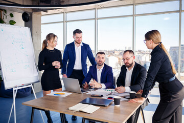 Business people working together in a modern office with cityscape view. The director tells the staff about new technologies. Office work concept