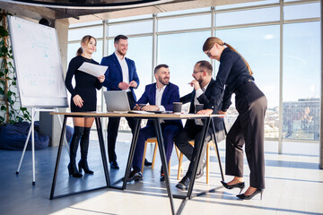 Business people working together in a modern office with cityscape view. The director tells the staff about new technologies. Office work concept