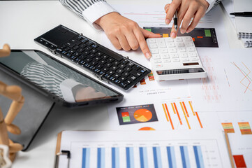 woman hand working on calculator and portable table analyzing graph chart.