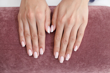 Female hand fingers nails with manicure after nail salon procedure on pink.