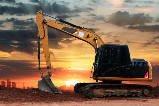 Excavators are digging the soil in the construction site on the sunset background