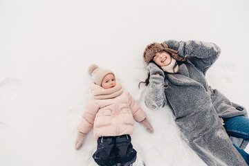 Mom and daughter in winter. Happy family enjoy winter snowy day. They hug, laugh, have fun, ride in the snow and enjoy the winter snowy weather