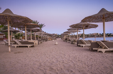 Beautiful sea coast.??Beach by the sea.??Wicker beach umbrellas and wind fences.??Conceptual image of a beach holiday.