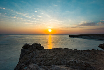 Beautiful sunrise at sea. Dawn on the Red Sea. The sun is reflected in the sea. Light clouds in the blue dawn sky. Tropical sunrise