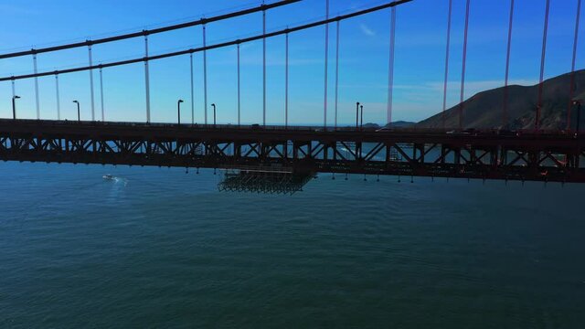 Aerial reveal of cars and trucks traveling on the San Francisco Golden Gate Bridge.