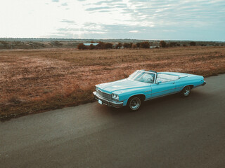 blue retro car on the road at sunset