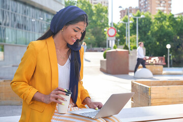 Young indian businesswoman working with a laptop outdoors.
