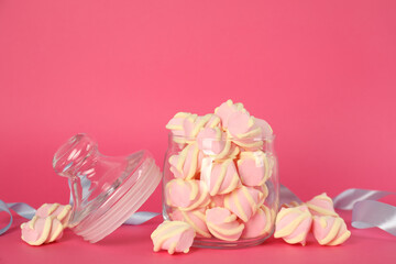 Glass jar with tasty marshmallows on bright pink background