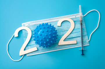 Covid-19 vaccine, diseases prevention and global coronavirus immunization campaign in 2021 concept with syringe with hypodermic needle, plastic virus model and face mask isolated on blue background