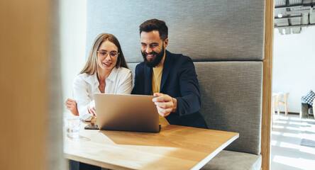 Two business professionals smiling at a laptop screen