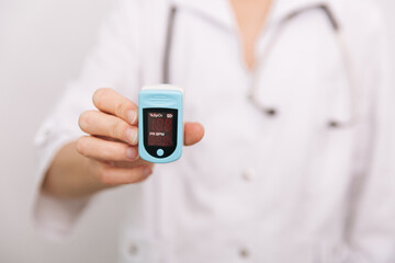 Pulse oximeter with hand of doctor isolated on white. Measuring oxygen saturation, pulse rate and oxygen levels. The concept of portable digital device to measure person's oxygen saturation.