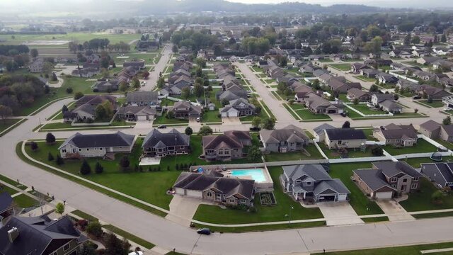Aerial view of newer residential neighborhood in western Wisconsin. Symmetrical lines of larger homes and yards. Perfectly landscaped properties. Sunny sky and lake in corner.