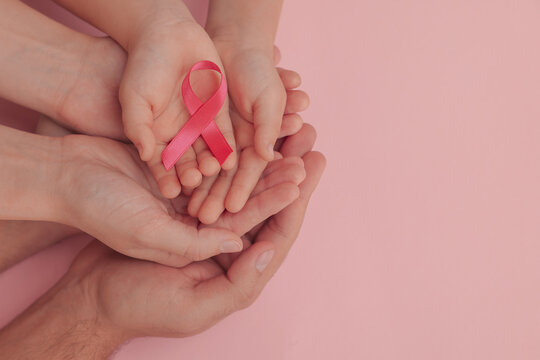 Family holding pink ribbon on color background, top view with space for text. Breast cancer awareness