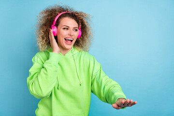 Photo of funny charismatic lady imagine herself dj wear earphones green hoodie isolated blue color...