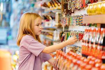 a funny little girl looks with interest at jewelry and souvenirs in the store. 