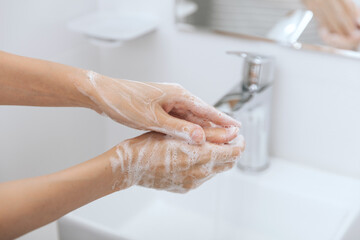 Washing hands under the flowing water tap. Hygiene concept hand detail. Washing hands rubbing with soap for corona virus prevention, hygiene to stop spreading corona virus in or public wash room.