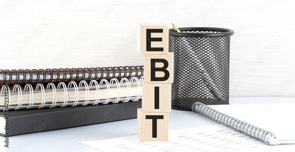 Poster ebit text on wooden block with notebooks on white background