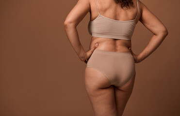Rear view of female body with flaws and imperfections isolated on beige background with copy ad...