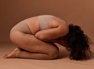 Depressed woman in underwear with cellulite and stretch marks covers her face, doesn't accept herself and body because of framework established by society. Self-acceptance and body positivity concept - obrazy, fototapety, plakaty