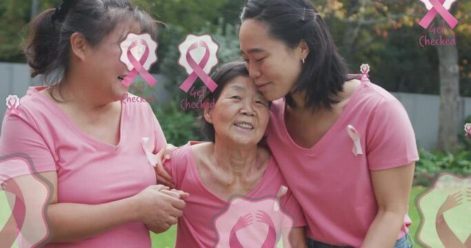 Animation of pink breast cancer ribbons over happy multi generation asian women embracing in garden