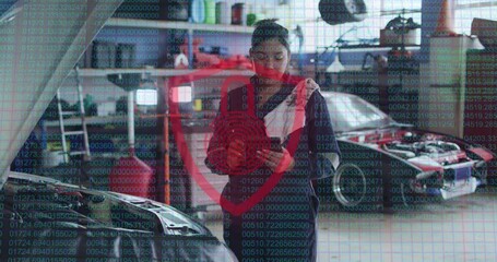 Animation of padlock and shield icon over biracial female car mechanic using tablet at garage - Powered by Adobe