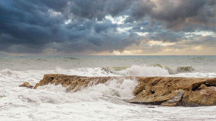 Storm clouds on breakwater at sunset