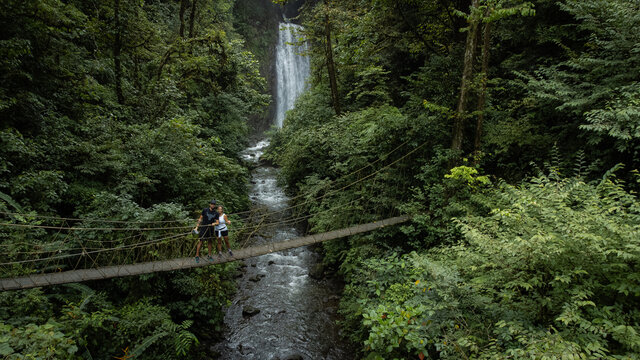 waterfall in the forest. Couple on a suspension bridge with a waterfall in the background of the image.  Travel through Costa Rica