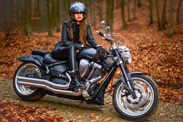 Fototapeta na wymiar A beautiful woman with long hair on a chopper motorcycle in autumn landscape.