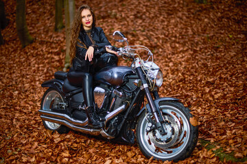 Fototapeta na wymiar A beautiful woman with long hair on a chopper motorcycle in autumn landscape.