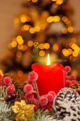 Burning red candle in Christmas season decorations, Decorated tree in the background. Selective focus. Holiday season background