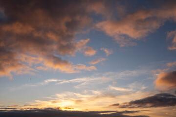 Stunning sunset cloudy sky. Low sun illuminates clouds in warm color. Nature background.