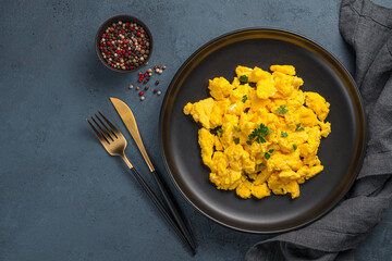 A portion of scrambled eggs with parsley on a dark background. Top view, horizontal. A recipe for...