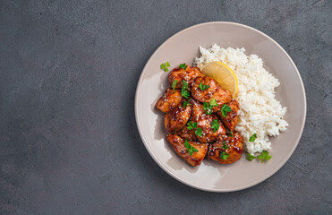 Juicy chicken in Teriyaki sauce served with rice, sesame seeds and lemon. Japanese Oriental cuisine.