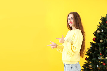 Attractive woman and Christmas tree on yellow background