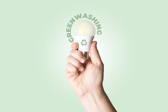 Greenwashing concept: male person hold a white battery with recycle symbol printed on it