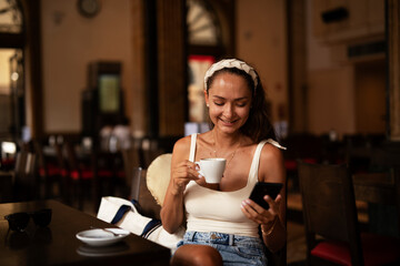 Stylish young woman drinking coffee at cafe. Beautiful girl enjoy in fresh coffee