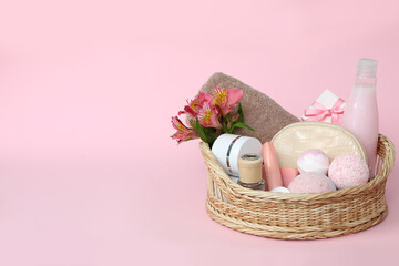 Wicker basket with cosmetics on pink background