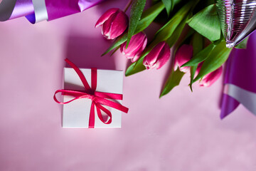 Top view pink tulips flowers in violet paper wrapper with gift box, festive background, concept of Happy Mother's day, Woman's day, birthday, 8 March, Valentines day
