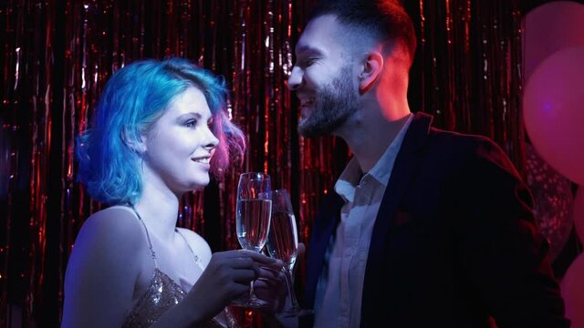 Romantic toast. Valentine Day party. Holiday date. Festive night celebration. Happy couple enjoying drink champagne together cheers in blue pink neon light with balloons tinsel.