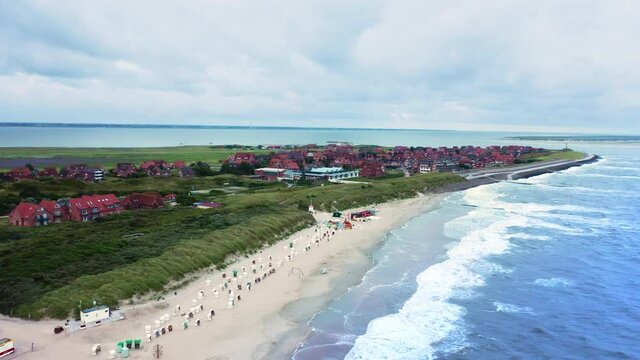 Aerial view of an island town with houses and a sandy beach washed by the waves, Gernamy, Baltrum.