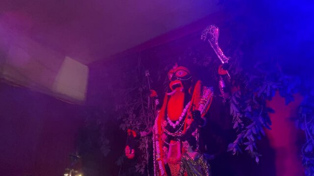  Close up side view of a Chamunda Kali at night with red and blue light smoke effect 