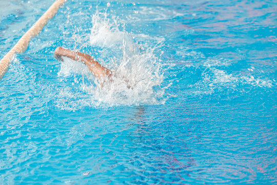 A swimmer swims quickly under the water in the pool. Blurry movement.