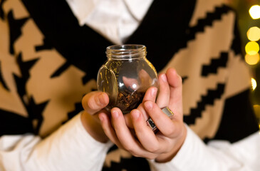 Close-up of a child's hand with a jar of spices - a clove on a bokeh background. Christmas spices concept 